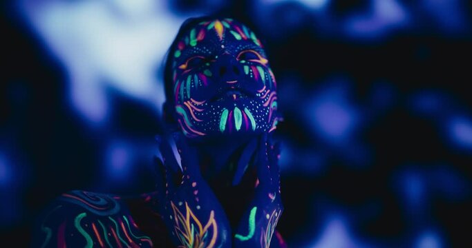 Expressive Female Dancer Transcends Boundaries with Contemporary Dance. Cinematic Portrait of a Young Creative Performer Covered in Neon Body Paint, Looking at Camera, Moving in Improvised Fashion