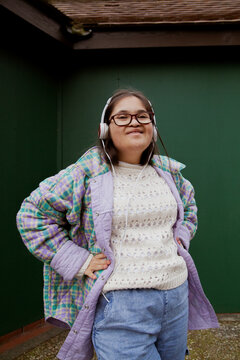 Young mid-sized woman with Down Syndrome posing in front of green wall
