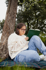 Fototapeta premium Curvy woman with Down syndrome reading in the park