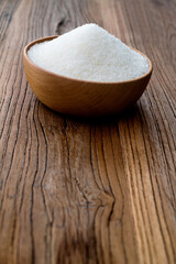 Fototapeta na wymiar Granulated sugar in a bowl on wooden table