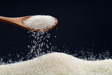 Sugar crystals falling out of wooden spoon