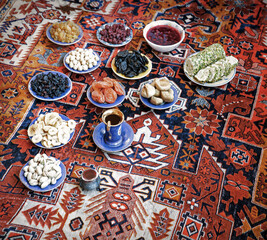 Eastern feast. Asian still life of dried fruits and nuts in plates on a carpet