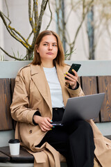 Amidst the hustle and bustle of city life, a businesswoman takes a break to complete her work,...