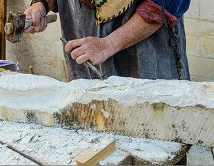 Medieval re-enactment of a stonemason shaping the stone with a hammer and chisel - Powered by Adobe