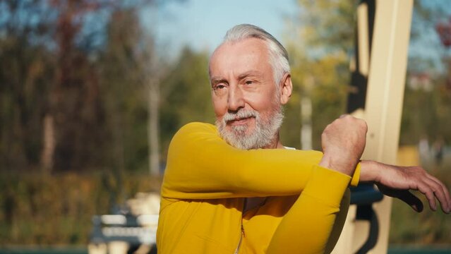 Happy senior man stretching before workout, training in outdoor gym, wellness