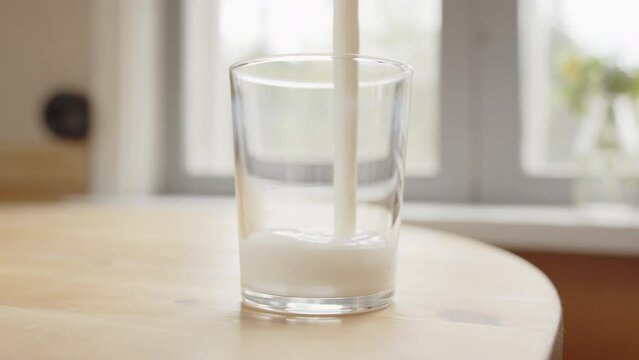 Healthy fermented milk kefir poured into glass on countertop, close-up