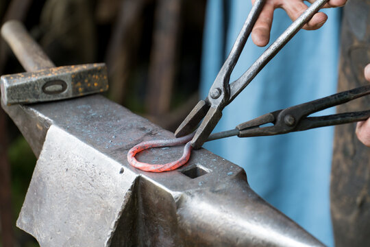 Blacksmith works glowing metal on an anvil