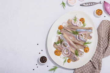 Salted herring with dijon mustard, dill and red onion rings on white stone background