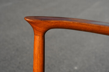 A danish mid century modern teak armchair from the 60s vintage standing in the dining living room with paper cord seat teak wood 50s 70s retro original isolated refurbished outside sunlight closeup