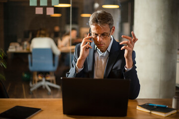 Businessman in office. Handsome man talking on phone at work..