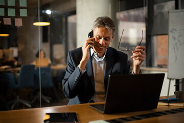 Businessman in office. Handsome man talking on phone at work..