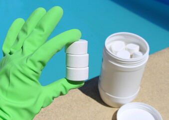 White mini chlorine tablet in the hand of a pool disinfection service worker. The beginning of the swimming season is a hot summer.