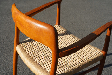 A danish mid century modern teak armchair from the 60s vintage standing in the dining living room with paper cord seat teak wood 50s 70s retro original isolated refurbished outside sunlight closeup