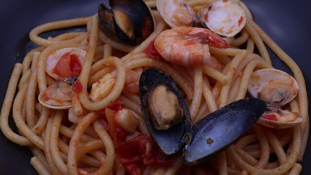Italian spaghetti allo scoglio in a black dish. Seafood spaghetti pasta.