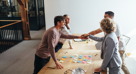 Professionals stacking hands together during a meeting in an office. Business team standing...