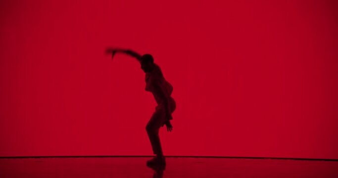 Male Dancer in White Clothes Unleashing an Energetic Fusion of Styles with Powerful Modern Dance Choreography, Swift Turns and Athletic Grace, Dancing in Front of an Solid Red Digital Screen