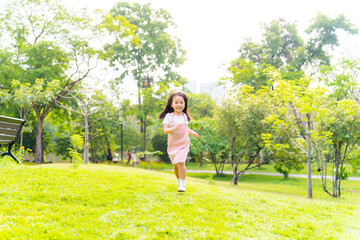 Little cute Asian girl playing and running at park in the city. 
Happy Asian family enjoy and fun outdoor lifestyle on summer holiday vacation. Family relationship and children development concept.