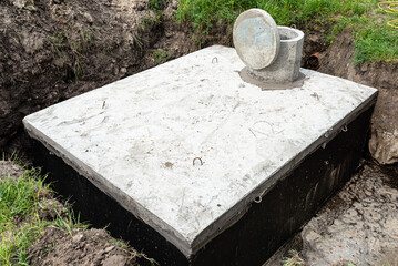 Concrete septic tank with a capacity of 10 cubic meters placed in the garden by the house, visible...