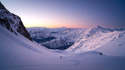 Skiers touring in winter, full of snow, at sunrise under a beautfiul clear sky full of colors....