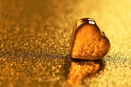 Amber glass heart on golden shiny table