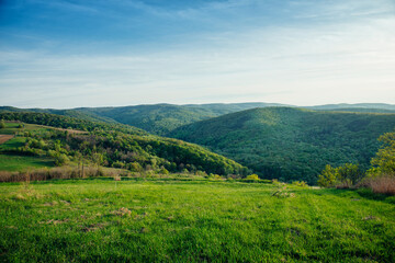 Fototapeta na wymiar Beautiful spring landscape in the mountains, grassy field and hills. The rural background of the beautiful countryside is sunny in the afternoon