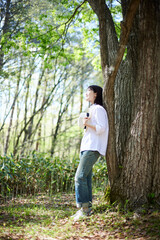 Naklejka premium 初夏の森でリラックスしながら森林浴を楽しむ30代日本人女性
