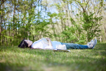 初夏の森で寝転びリラックスする30代日本人女性