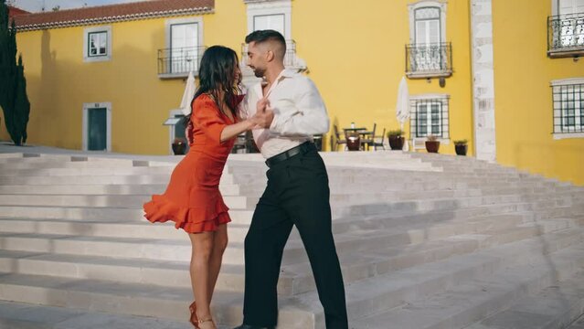 Latin performers practicing dance on town stairs. Happy couple dancing outdoors.