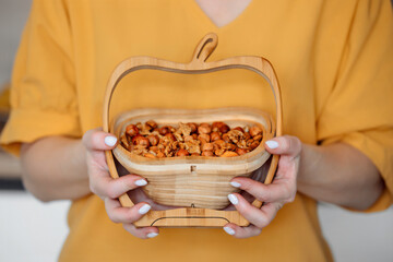 female hands hold close-up wooden basket with nut mix, almonds, hazelnuts, walnut