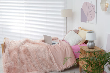 Stylish teenager's room interior with comfortable bed and laptop