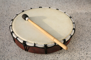 Drum and drumstick on grey table, closeup. Percussion musical instrument