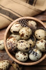 Obraz premium Speckled quail eggs and feathers on wooden table, top view