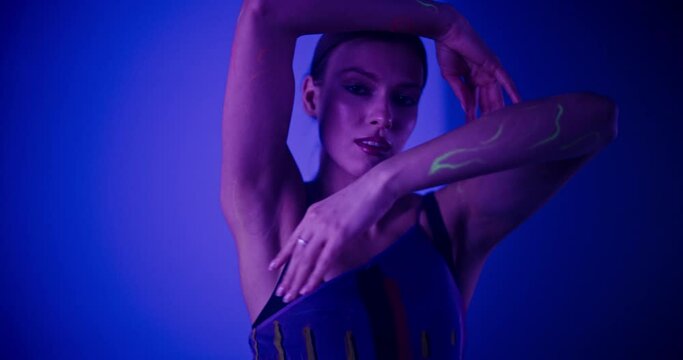 Young Beautiful Girl Embodies Modern Dance with Colorful Paint on Her Body in a Dark Studio, Creating Mesmerizing Visual Language and Vibrant Expressive Energy with Her Performance