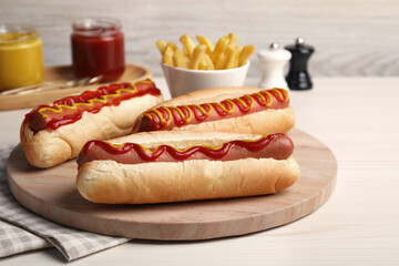 Fresh delicious hot dogs with sauces on white wooden table