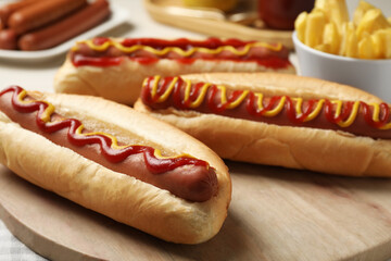 Fresh delicious hot dogs with sauces on wooden board, closeup