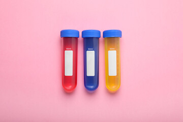Test tubes with colorful liquids on pink background, flat lay. Kids chemical experiment set