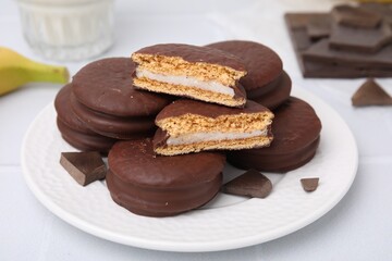 Tasty banana choco pies and pieces of chocolate on white table, closeup