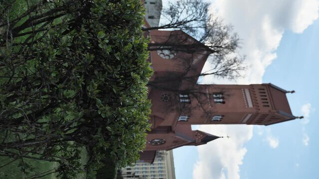 The Catholic Church of Saints Simon and Helen. Red Catholic Church in Minsk, a listed architectural monument of national importance. Green bushes in the foreground. Vertical video