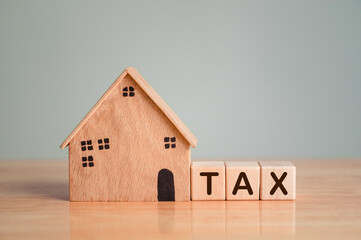 Property tax or house tax with wooden model on table top background. Business loan and real estate investment concept.