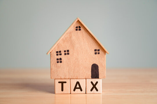 Property tax or house tax with wooden model on table top background. Business loan and real estate investment concept.