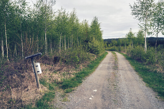 a post box by the gravel road in the forest