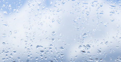 Raindrops on the glass, blue sky and clouds in the background
