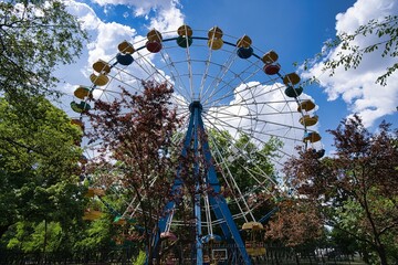 Ferris wheel in the park with a cloudy blue sky in the background - Powered by Adobe