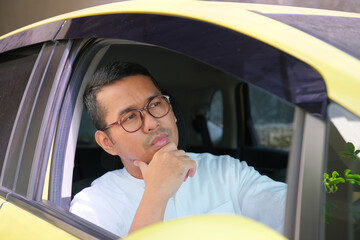 Adult Asian man driving his car with sad expression