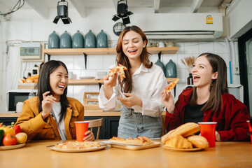 Group of friends making fun at home party.They sitting on desk in living room and eating pizza. happy