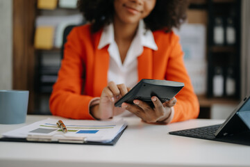 Businesswoman hands working with finances about cost and calculator and laptop with tablet, smartphone at office