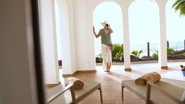 Reveal female wearing sunhat checking into luxury hotel 