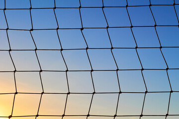 Net to catch balls around a football field, on clear blue sunset sky background