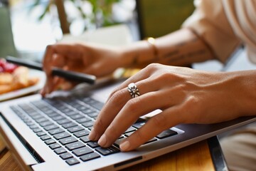 Selective focus of a female person working on a laptop in a cafe