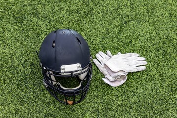 Top view shot of a football helmet and a pair of white gloves on the green grass
